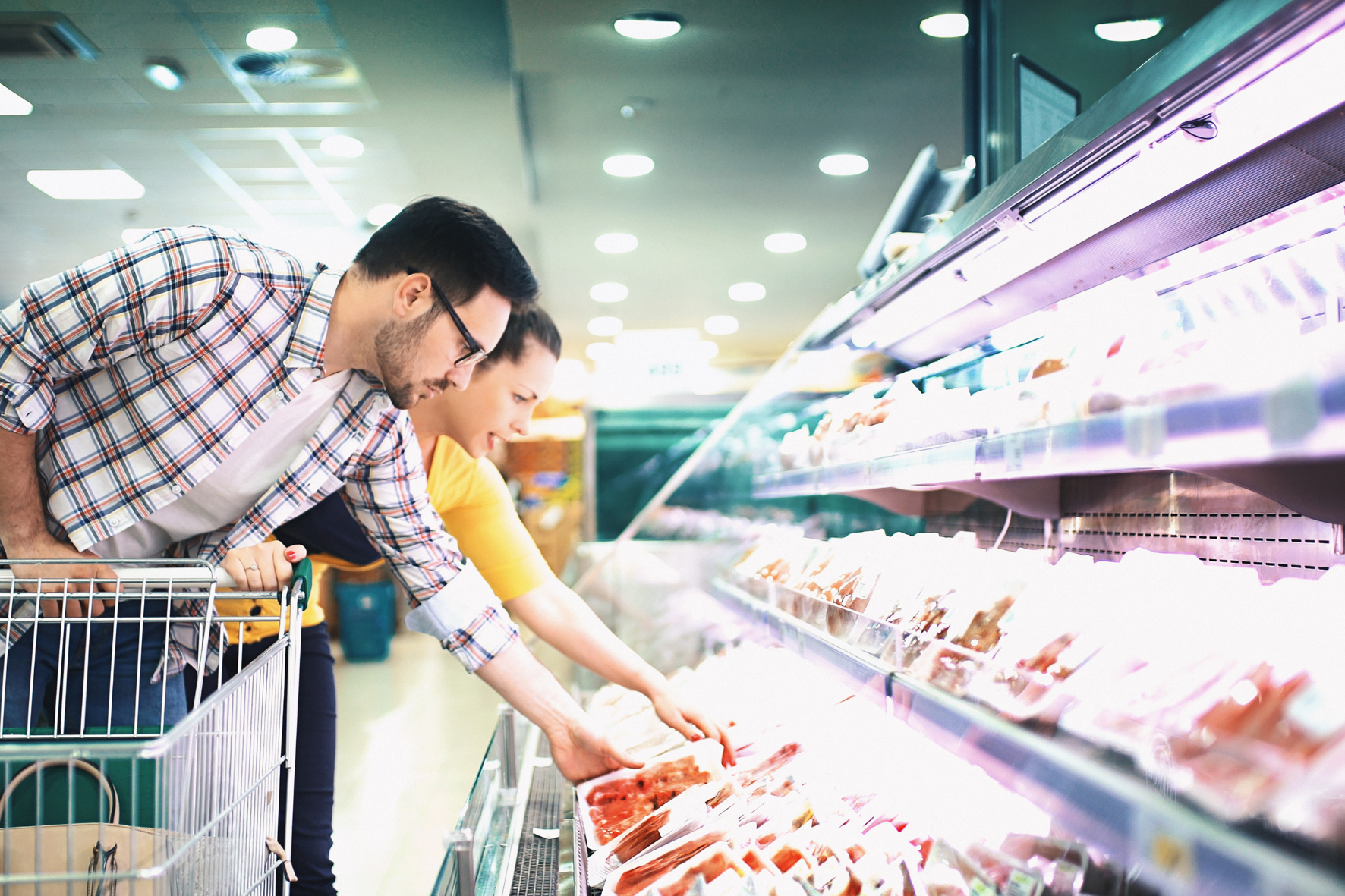 a man and woman looking at food in a grocery store